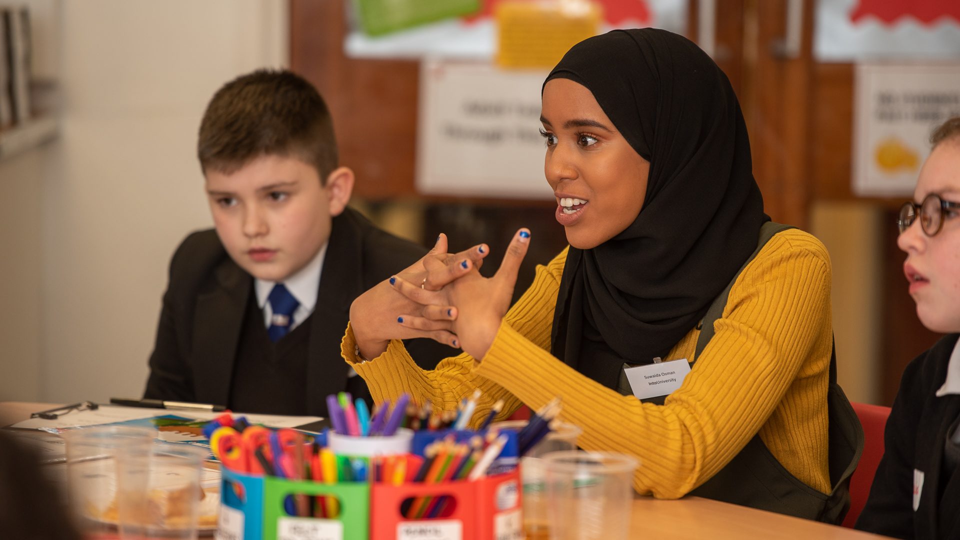 Suwaida Osman (Centre Leader at IntoUniversity Birmingham North) sat on a table with students at the centre launch.